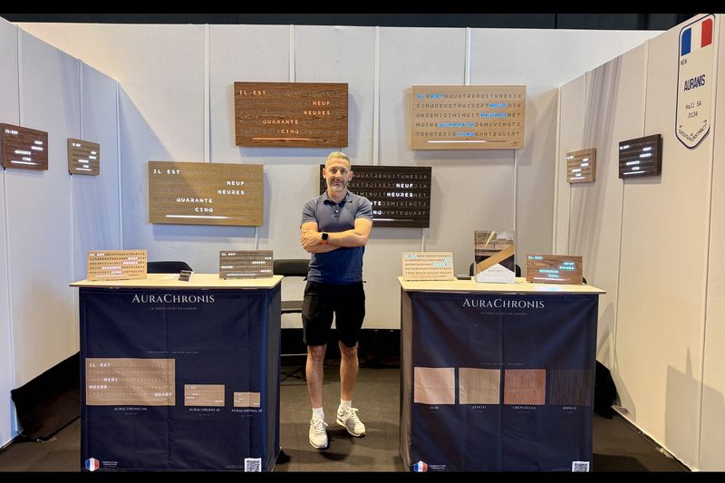 Olivier Haro sur le stand Aurachronis au salon Maison & Objet, entouré d'horloges à mots